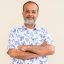 Portrait of handsome Indian man with gray beard against plain wall